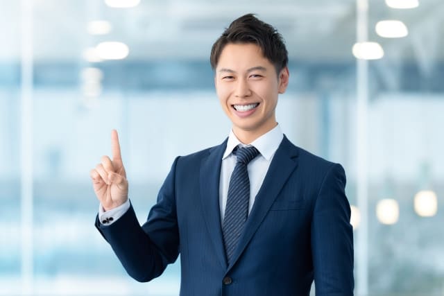 人差し指を立てて案内する男性